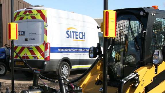 one white vehicles in the background and a construction vehicle